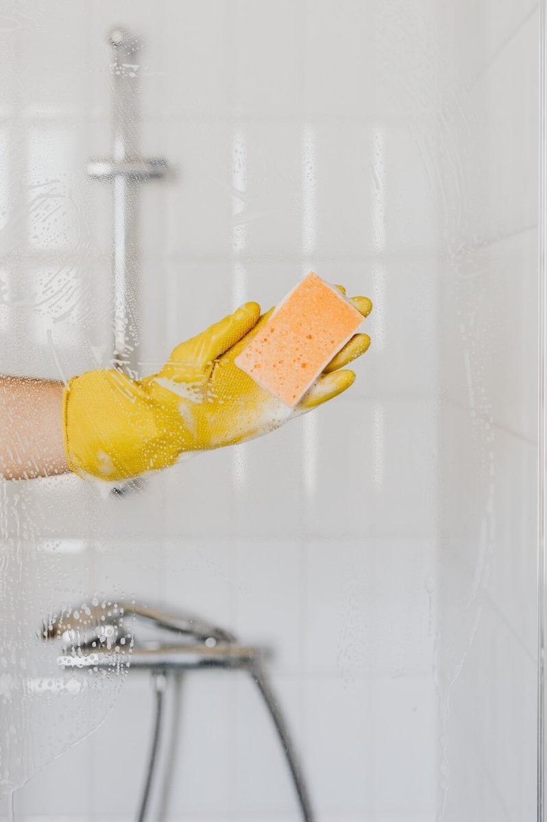 Ruka osobe koja čisti staklo tu&scaron; kabine u žutim gumenim rukavicama