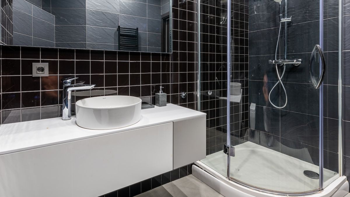 Tu&scaron; kabina s crnim pločicama u malom kupatilu