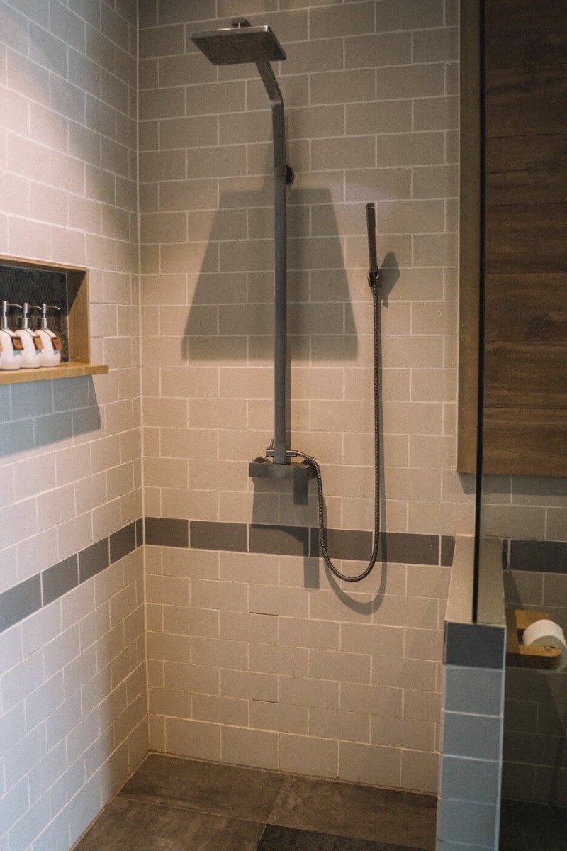 Polu-otvorena tu&scaron; kabina u kupatilu s pločicama krem boje